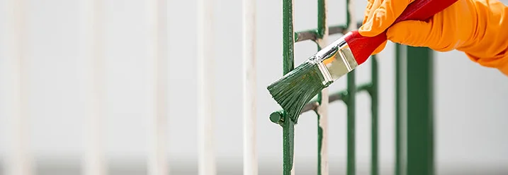 Hand in Handschuh streicht Metallzaun